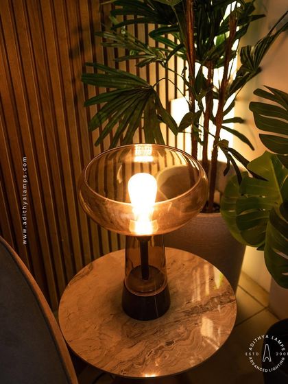 This simple and elegant table lamp features a warm filament bulb within a smoked glass shade. It's a perfect companion for a side table, providing a cozy and inviting ambient light for any corner.
