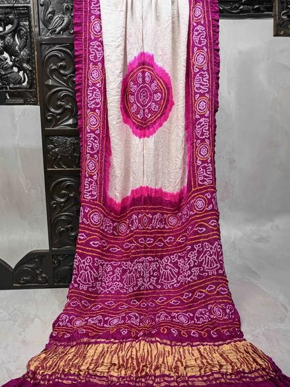A beautiful Bandhani saree in a combination of off-white and magenta. The intricate patterns and elephant motifs along the border are simply stunning.