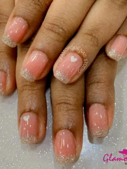 A soft and sweet design featuring a sheer pink base, delicate silver glitter French tips, and a tiny white heart accent.
