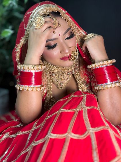 A thoughtful pose from a bride in her red lehenga. The lighting beautifully captures the shimmer in her eye makeup and the richness of her outfit.