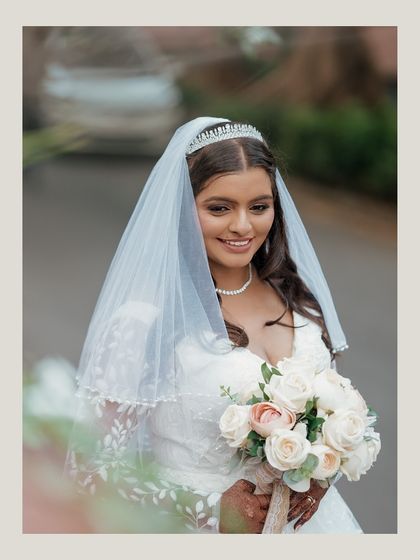 A beautiful portrait of the bride in her white gown, holding her bouquet, the picture of grace and happiness.