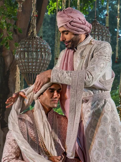 A tender moment between two grooms, highlighting the intricate details of their coordinated sherwanis and turbans. This image captures the personal stories we are privileged to be a part of.