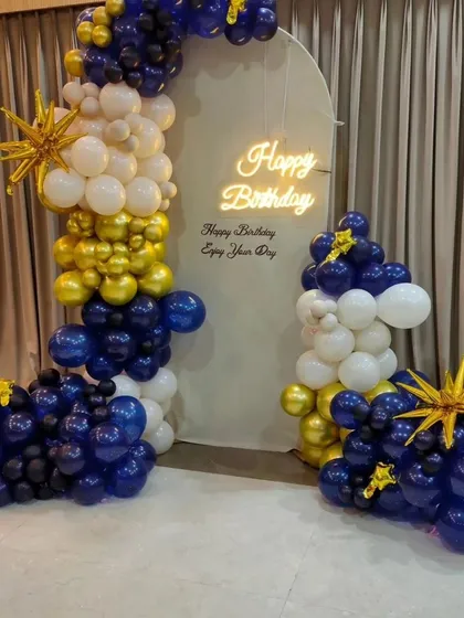 A stylish birthday backdrop in royal blue, gold, and white, with a personalized message and a neon sign.