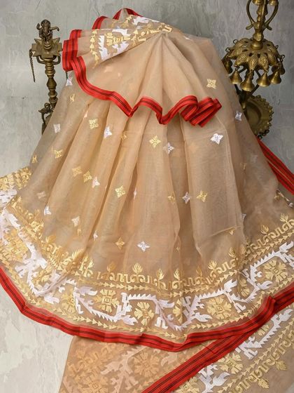 A delicate beige organza-cotton saree with intricate white and gold Jamdani weaving. The red scalloped border adds a beautiful pop of color to this ethereal piece.