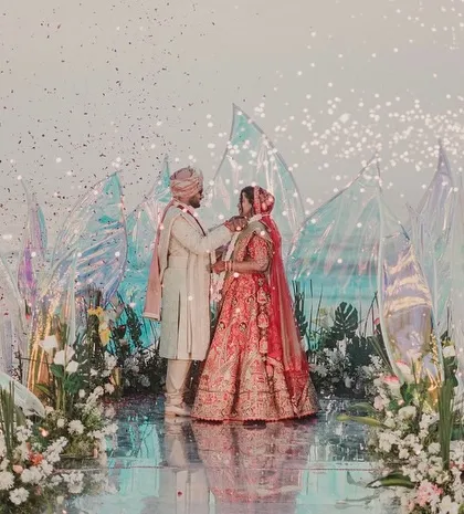 The Jaimala exchange at a stunning beach wedding. The modern, iridescent mandap I designed reflects the light from the sparklers, creating a dazzling, magical effect.
