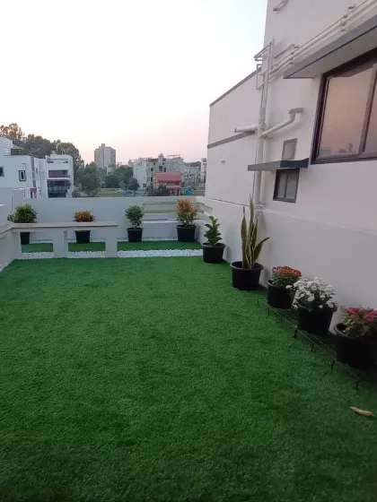 Another view of the terrace, showing how the artificial grass provides a clean, green floor for the entire space, complemented by potted plants along the wall.