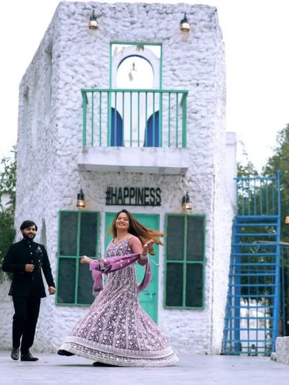 A beautiful pre-wedding shot with the bride twirling in her gorgeous lehenga. The Santorini-style backdrop adds a touch of destination wedding magic to the photo.