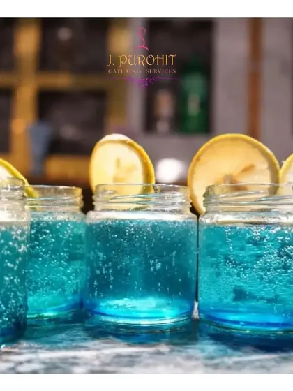 Handling beverage service for large events is my specialty. This image shows a batch of my signature blue mocktails, ready to be served in chilled mason jars with fresh lemon garnishes. This setup ensures that every guest receives a consistently beautiful and refreshing drink without delay.