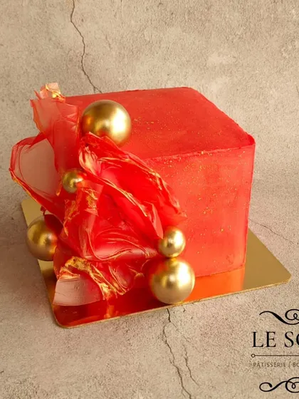 This fiery red cube cake makes a bold and modern statement. A 1.5 kg Chocolate Biscoff cake, it's decorated with abstract red rice paper sails, touches of gold leaf, and elegant gold spheres, perfect for a grand celebration.