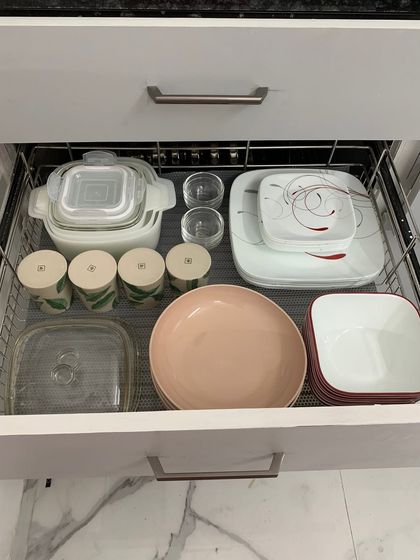 A pull-out wire basket drawer with everyday plates, bowls, and storage containers. The open design allows for air circulation and makes it easy to see everything.