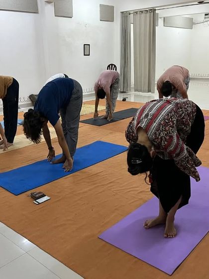 Participants in a standing forward bend, a common posture in Hatha Yoga that calms the nervous system.