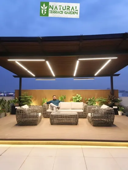 A completed rooftop project in Gurgaon featuring a large pergola over a composite wood deck. This setup creates an ideal outdoor lounge, complete with comfortable wicker furniture, integrated planters, and modern linear LED lighting for a sophisticated evening atmosphere.