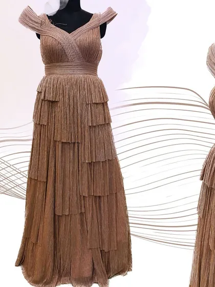 A studio view of the shimmered rose gold gown, showing the sculpted shoulders and the beautifully layered and pleated skirt.