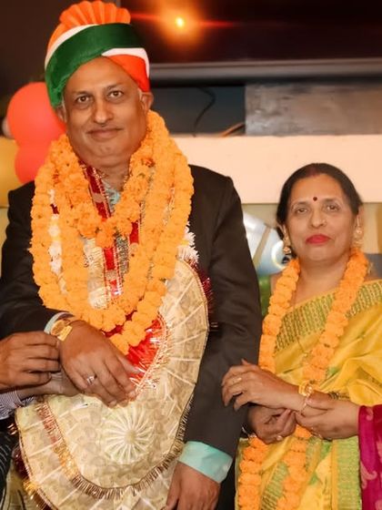 A formal group portrait of a family celebrating a special occasion, adorned with garlands.