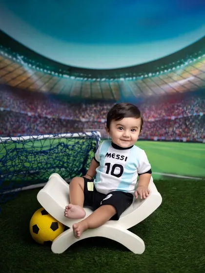 For the future football star! This baby is dressed in a Messi jersey, sitting in front of a stadium backdrop for a sporty themed shoot.