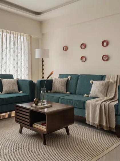 A cozy living room setup featuring a beautiful teal sofa that adds a pop of color. The mid-century modern coffee table and minimalist wall decor create a clean, uncluttered look, while the warm lighting makes the space feel inviting.