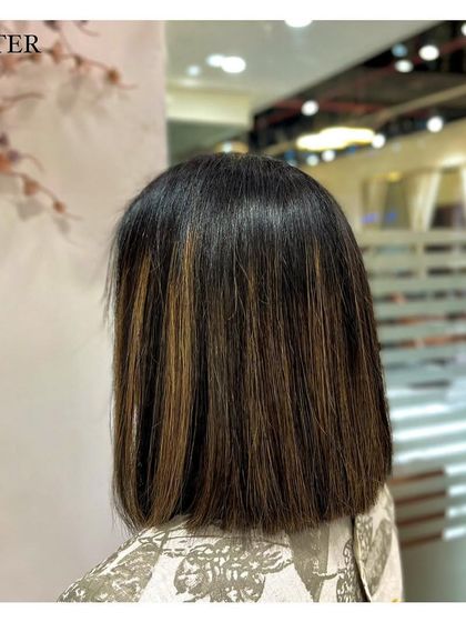 This client opted for a chic blunt haircut with some subtle brown highlights. The straight styling emphasizes the clean lines of the cut and the dimension of the color.