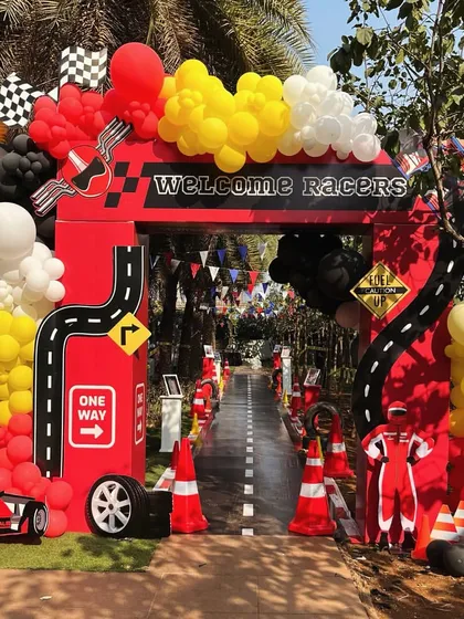 Welcome to the fast lane. This grand entrance arch for a Ferrari-themed birthday party sets the high-energy tone from the moment guests arrive, complete with a custom racetrack walkway and racing-inspired balloon garlands.