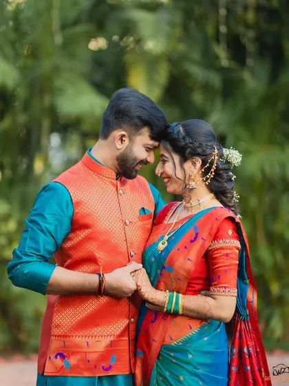 An intimate portrait of Varad and Dr. Rutuja in their vibrant, coordinated traditional outfits. The natural setting complements the bright colors perfectly.