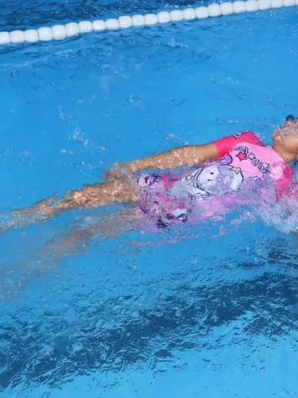 Our indoor swimming pool provides the perfect setting for aquatic education and fun. This action shot captures a young swimmer practicing her backstroke, demonstrating the confidence and technique she has developed during our structured swimming lessons for children.