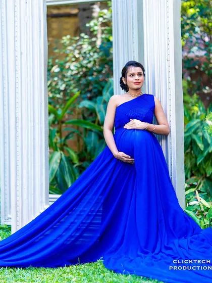 A stunning maternity shot with a flowing blue gown against the backdrop of our white garden frames.