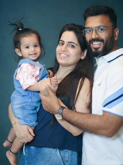 A sweet portrait of parents with their little girl. Her tiny wave and happy expression make this a truly memorable photo.