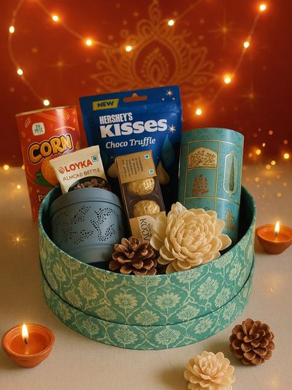 This Festival of Lights hamper is set against a warm, glowing background. The printed round box is filled with Hershey's Kisses, a trail mix, a festive lantern, and Ferrero Rocher, making it a sweet and joyful gift.