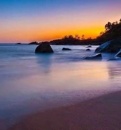 A long-exposure shot of a beautiful sunset at a rocky beach in Gokarna, creating a dreamy, colorful scene.