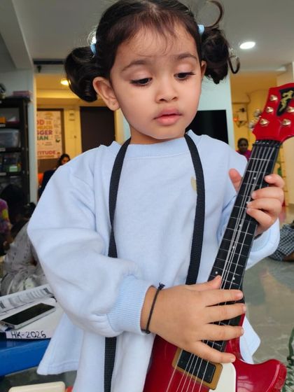 Getting into character with a toy guitar, this little one is learning about stage presence and creative expression.