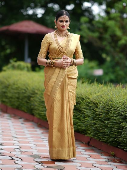 A full-length shot of a client in a monochromatic gold Kanchivaram ensemble. The blouse is made from the same fabric as the saree for a seamless, elegant look.