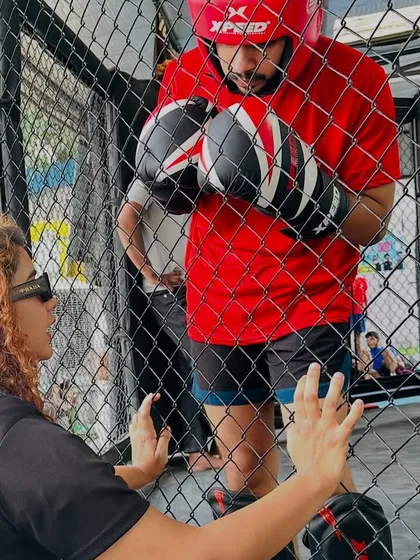 A coach gives last-minute advice to a fighter through the cage. This close bond and trust are crucial for success.