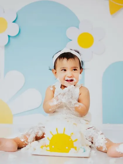 A round of applause for a successful cake smash. Her happy, frosting covered hands tell the whole story of her fun first birthday experience.