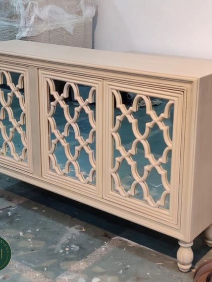 This elegant sideboard features mirrored doors with a beautiful wooden lattice overlay. The turned legs add a classic touch, making it a timeless piece for storing dinnerware or other household items.