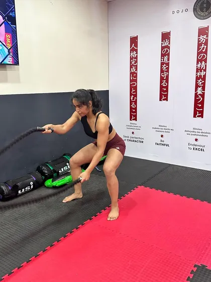 A female student builds her upper body and core strength with battle ropes, a staple in our high-intensity conditioning circuits.