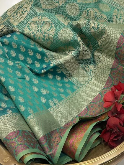 The artistry of the weave. This is a close-up of a teal green Chanderi saree, highlighting the delicate blend of silk and cotton with golden zari butis and a contrasting border, a testament to its lightweight luxury.