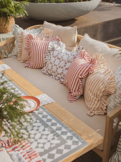 A close-up of the ruffled and patterned cushions that add softness and a touch of country charm to the wooden benches.