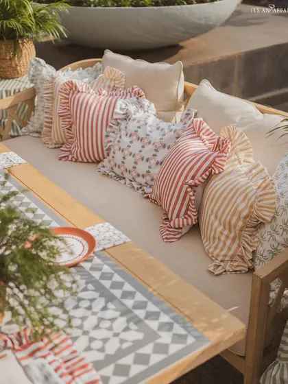 A close-up of the ruffled and patterned cushions that add softness and a touch of country charm to the wooden benches.