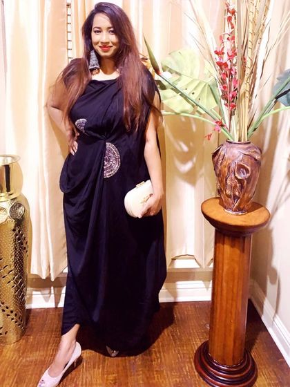 This client is rocking a modern draped dress in black. She has styled it with bold, oversized silver earrings and a simple clutch, creating a very chic and contemporary look.