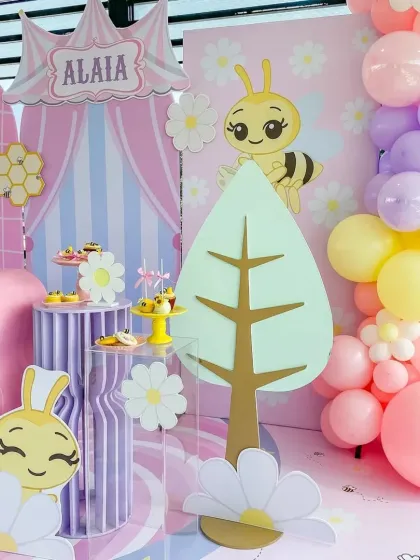 A closer look at the bee-themed decor, with cute bee and flower cutouts, a pastel balloon garland, and themed dessert stands.