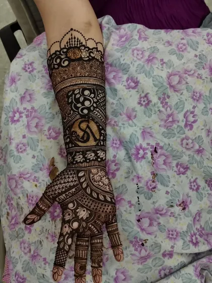 A modern take on traditional mehandi, with a stylish initial "S" incorporated into a design of paisleys and florals.