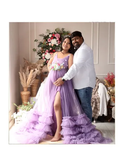 A beautiful couple portrait in our boho studio, surrounded by flowers and natural textures. The mom-to-be is stunning in a flowing lavender gown.