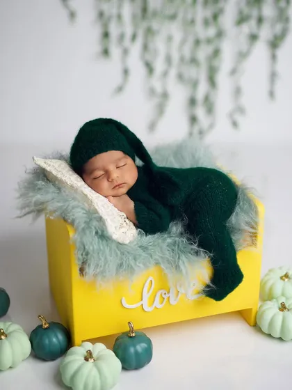 The same setup, but with the baby in a cute, matching green knit outfit and sleepy hat.