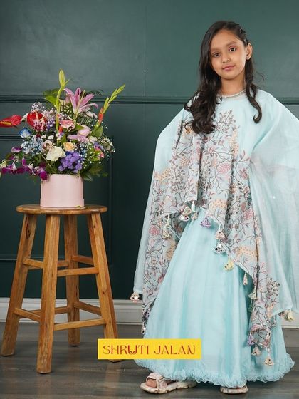 A beautiful shot of my sky blue cape set. The flowing cape is adorned with floral prints and tassels, creating a graceful and whimsical look for any little girl.