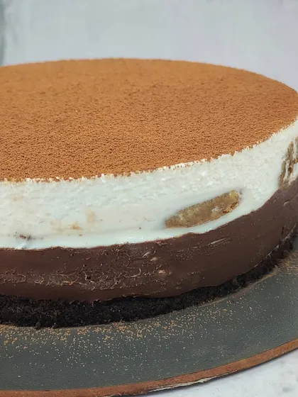 A close-up of the creamy layers in our Tiramisu Cheesecake. You can see the coffee-soaked sponge nestled inside.