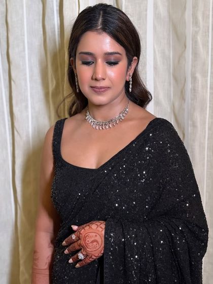 A different look for the groom's sister, this time a smokey eye for a cocktail night in a black sequin saree.