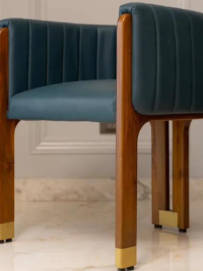 This artistic accent chair, made from teak wood and leather with brass-capped legs, is a crown jewel for a well-curated living room.