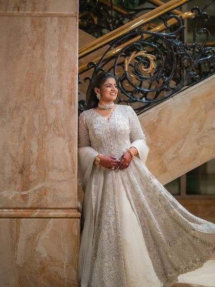 Posing by the grand staircase, the bride looks like royalty in her ivory Sangeet ensemble. The intricate embroidery catches the light beautifully, making her shine.