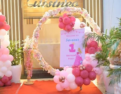The entrance to Samaira's royal celebration, featuring a circular arch decorated with flowers and pink balloons.