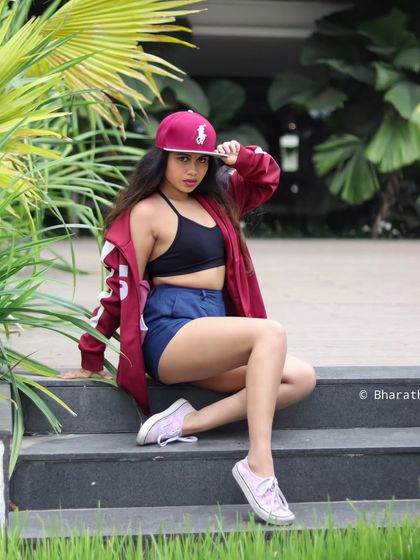 A confident pose that showcases a sporty and casual look. The lush background provides a great contrast.