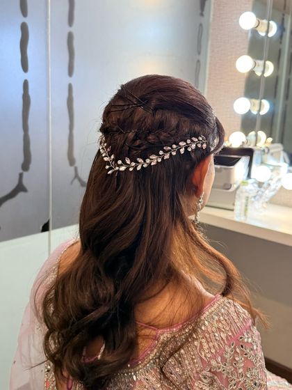 A detailed view of an intricate braided half-up hairstyle. Adorned with a delicate, leaf-patterned hair accessory, this style is perfect for weddings and festive occasions.